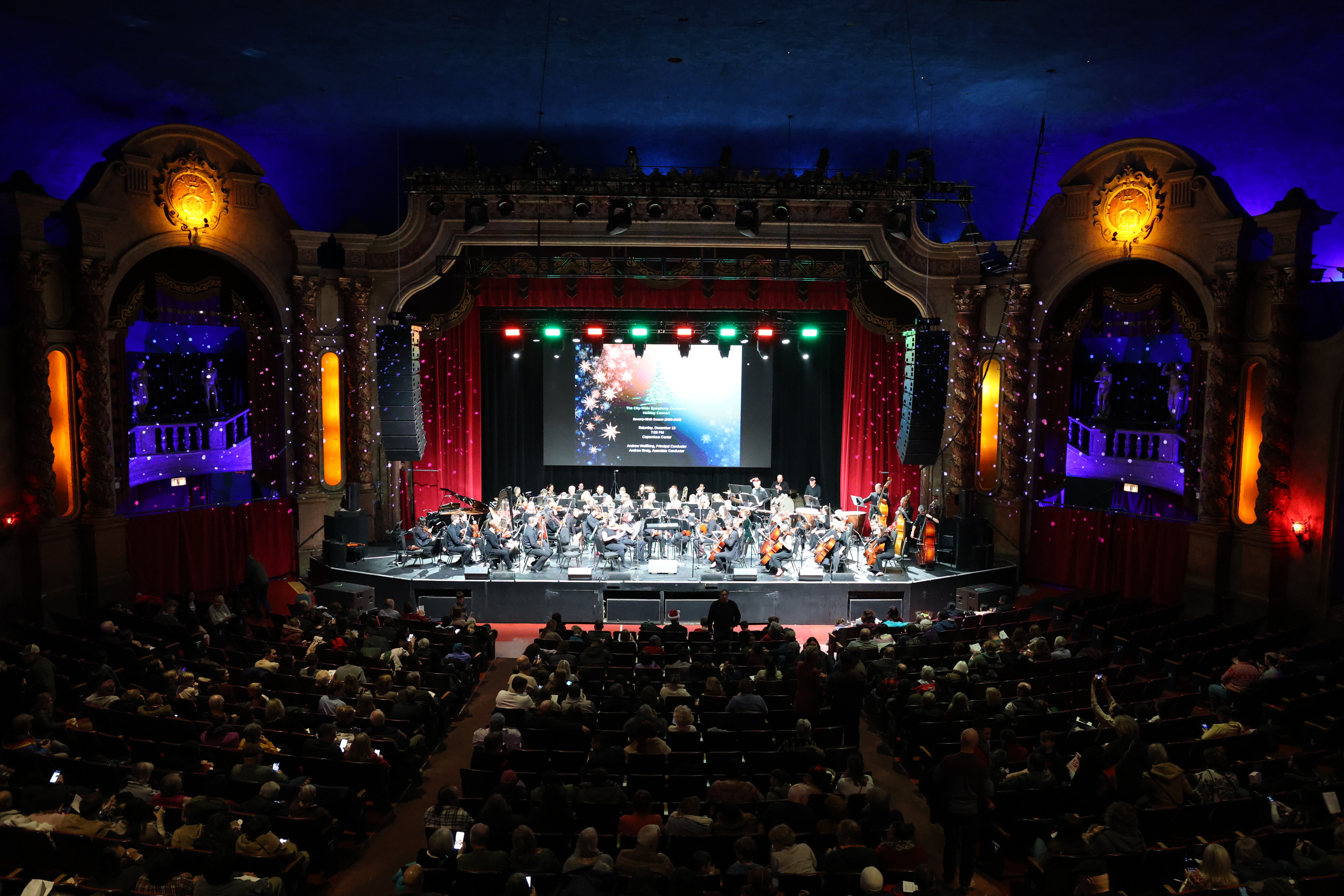 Orchestra performing on stage for a seated audience.